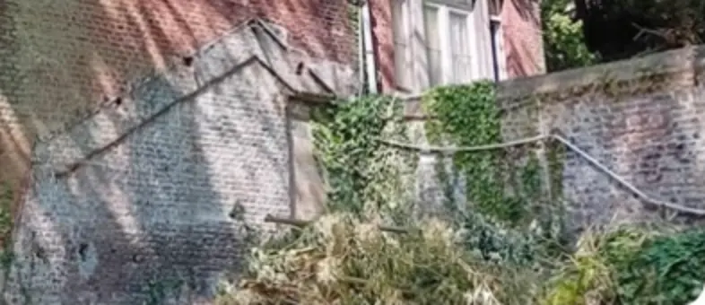 Détail de la photo de la Ville : maçonnerie en moellons contre le pignon nord-est et mur perpendiculaire couvert de lierre.